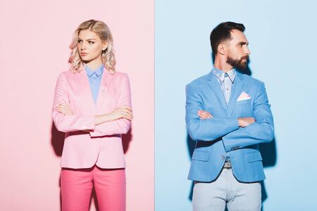 sad woman and handsome man with crossed arms on pink and blue backgroundの写真素材