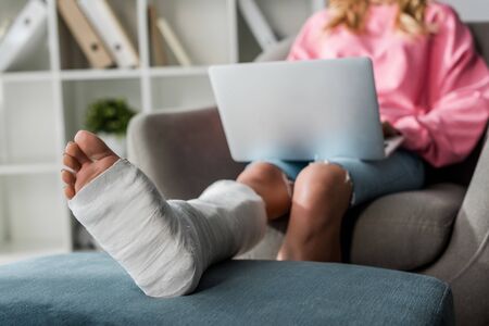 cropped view of injured woman working from home with laptopの写真素材