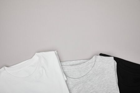 top view of blank basic black, white and grey t-shirts isolated on greyの写真素材