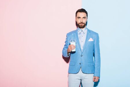 serious man holding cocktail on pink and blue backgroundの写真素材