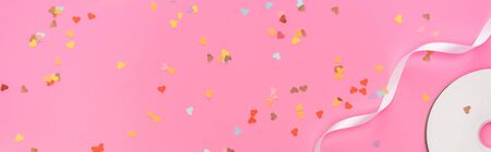 top view of valentines confetti, empty compact disk, ribbon on pink background, panoramic shotの写真素材