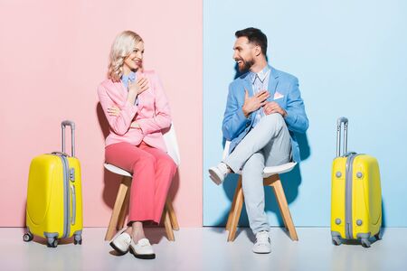 smiling woman and handsome man looking at each other on pink and blue backgroundの写真素材