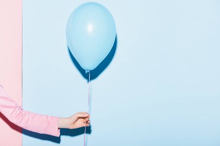 cropped view of woman holding balloon on pink and blue backgroundの写真素材