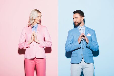 attractive woman and smiling man with praying hands on pink and blue backgroundの写真素材
