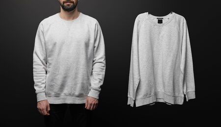 cropped view of bearded man near blank basic grey sweatshirt isolated on black