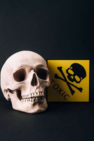 Skull and yellow toxic sign isolated on blackの写真素材