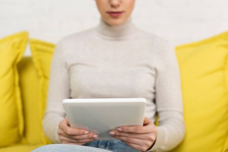 Cropped view of girl using digital tablet on sofaの写真素材