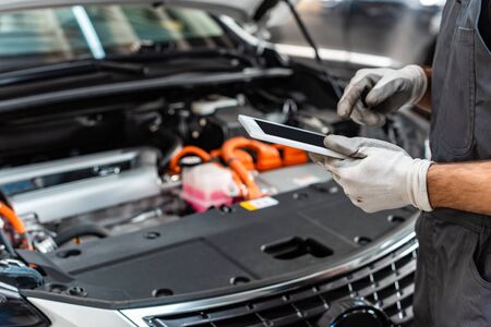 partial view of mechanic using digital tablet near car engine compartmentの写真素材