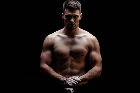 sexy muscular bodybuilder with bare torso with talcum powder on hands isolated on blackの写真素材