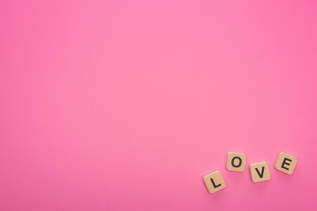 top view of wooden blocks with love lettering isolated on pinkの写真素材