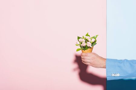 cropped view of man holding bouquet on pink and blue backgroundの写真素材