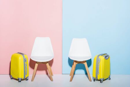 wooden chairs and travel bags on pink and blue backgroundの写真素材