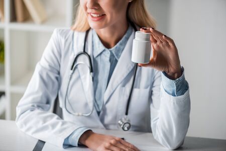 cropped view of happy doctor holding bottle with pillsの写真素材