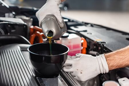 cropped view of mechanic pouring oil to car engineの写真素材