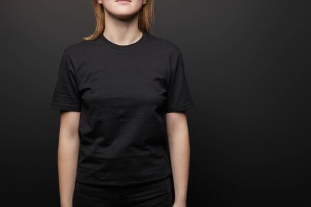 cropped view of woman in blank basic black t-shirt on black backgroundの写真素材