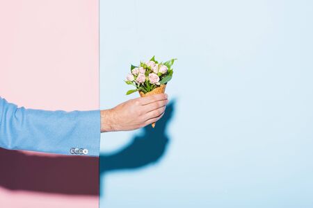 cropped view of man holding bouquet on pink and blue backgroundの写真素材