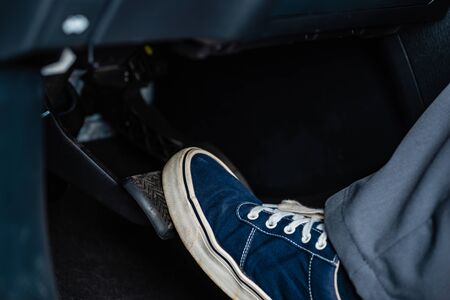 partial view of mechanic in sneakers pressing brake pedal in carの写真素材