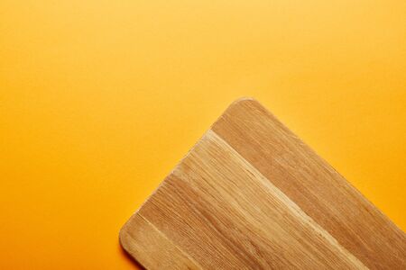 top view of wooden cutting board on orange backgroundの写真素材