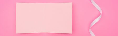 top view of empty paper card with ribbon isolated on pink, panoramic shotの写真素材