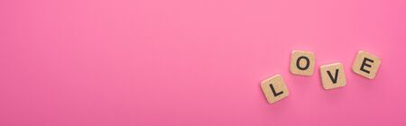 top view of wooden blocks with love lettering isolated on pink, panoramic shotの写真素材