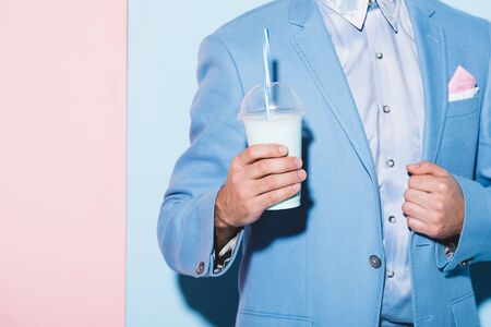 cropped view of man holding cocktail on pink and blue backgroundの写真素材