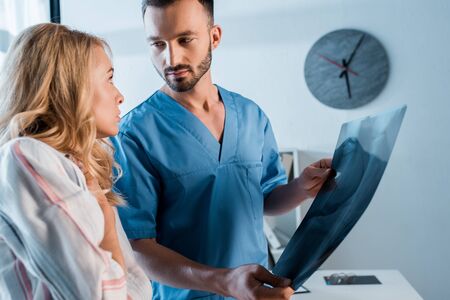 displeased woman looking at bearded orthopedist with x-ray