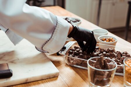 cropped view of woman taking dark chocolate cubesの写真素材