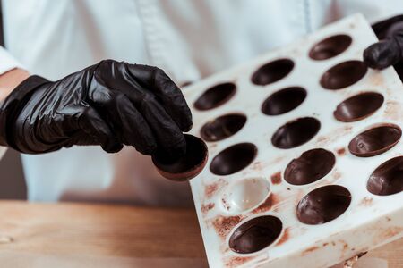 cropped view of chocolatier holding chocolate candyの写真素材