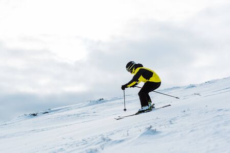 sportsman in helmet and goggles skiing on slope in wintertimeの写真素材