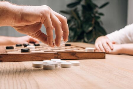 Side view of man holding white checkers while playing with woman at tableの写真素材