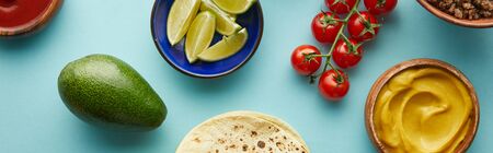 Top view of tortillas with fresh ingredients for taco on blue background, panoramic shot