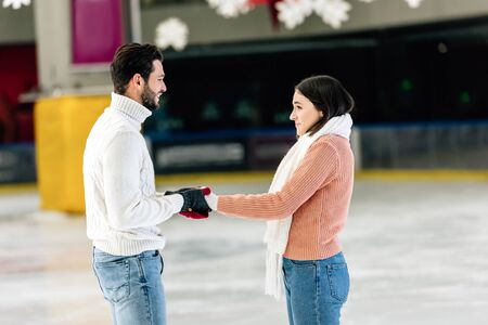 beautiful happy couple holding hands on skating rinkの写真素材