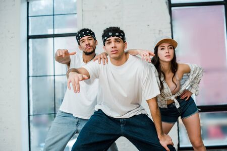 stylish multicultural dancers posing while dancing hip-hop in dance studioの写真素材