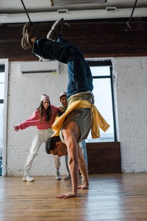 selective focus of man doing handstand while breakdancing near multicultural dancers