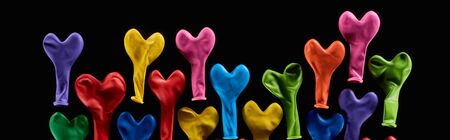 Top view of colorful rubber balloons in heart shape isolated on black, panoramic shotの写真素材