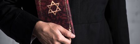 panoramic shot of young jewish man holding tanakh