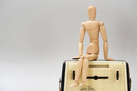 Wooden doll on vintage radio isolated on greyの写真素材