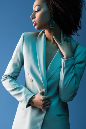 attractive african american woman in suit isolated on blueの写真素材