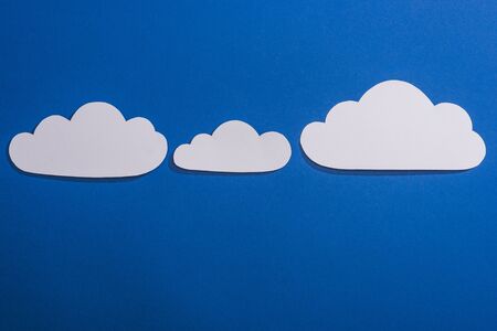 top view of white paper cut clouds on blue backgroundの写真素材