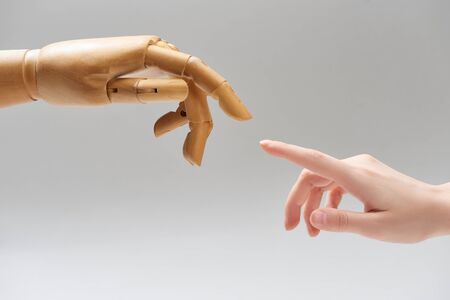 Cropped view of woman and hand of wooden doll pulling fingers to each other isolated on greyの写真素材