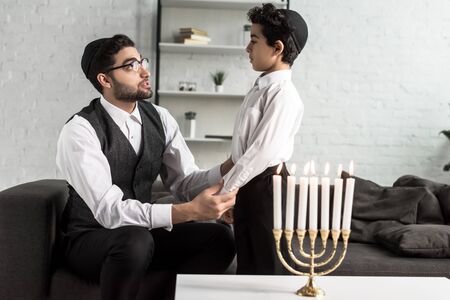 jewish father and cute son holding hands in apartmentの写真素材