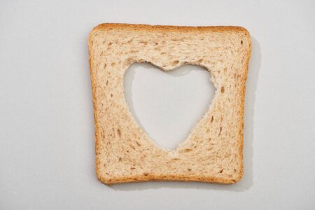 Top view of bread slice with carved heart shape on grey backgroundの写真素材