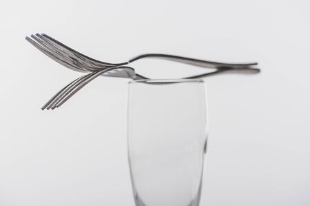 Selective focus of forks on clear champagne glass isolated on greyの写真素材