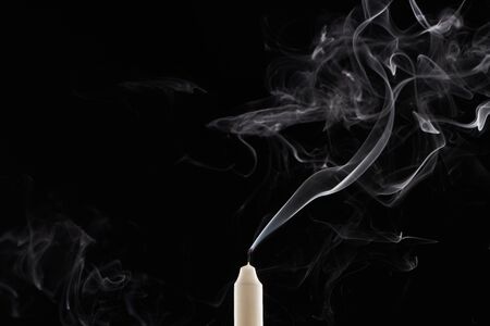 extinct white candle with smoke on black backgroundの写真素材