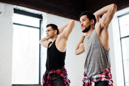 muscular multicultural dancers posing while dancing jazz funk in dance studio