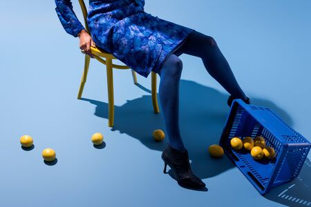 cropped view of african american woman sitting on chair on blue background