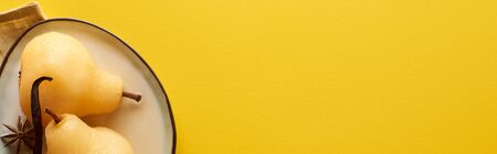 top view of delicious pear in wine with anise on plate on napkin on yellow background, panoramic shotの写真素材