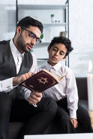 handsome jewish father and son reading tanakh in apartmentの写真素材