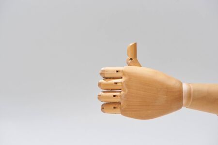 Hand of wooden doll with thumb up gesture isolated on greyの写真素材