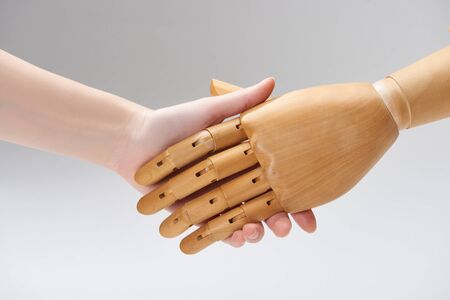 Cropped view of woman and wooden doll shaking hands isolated on greyの写真素材